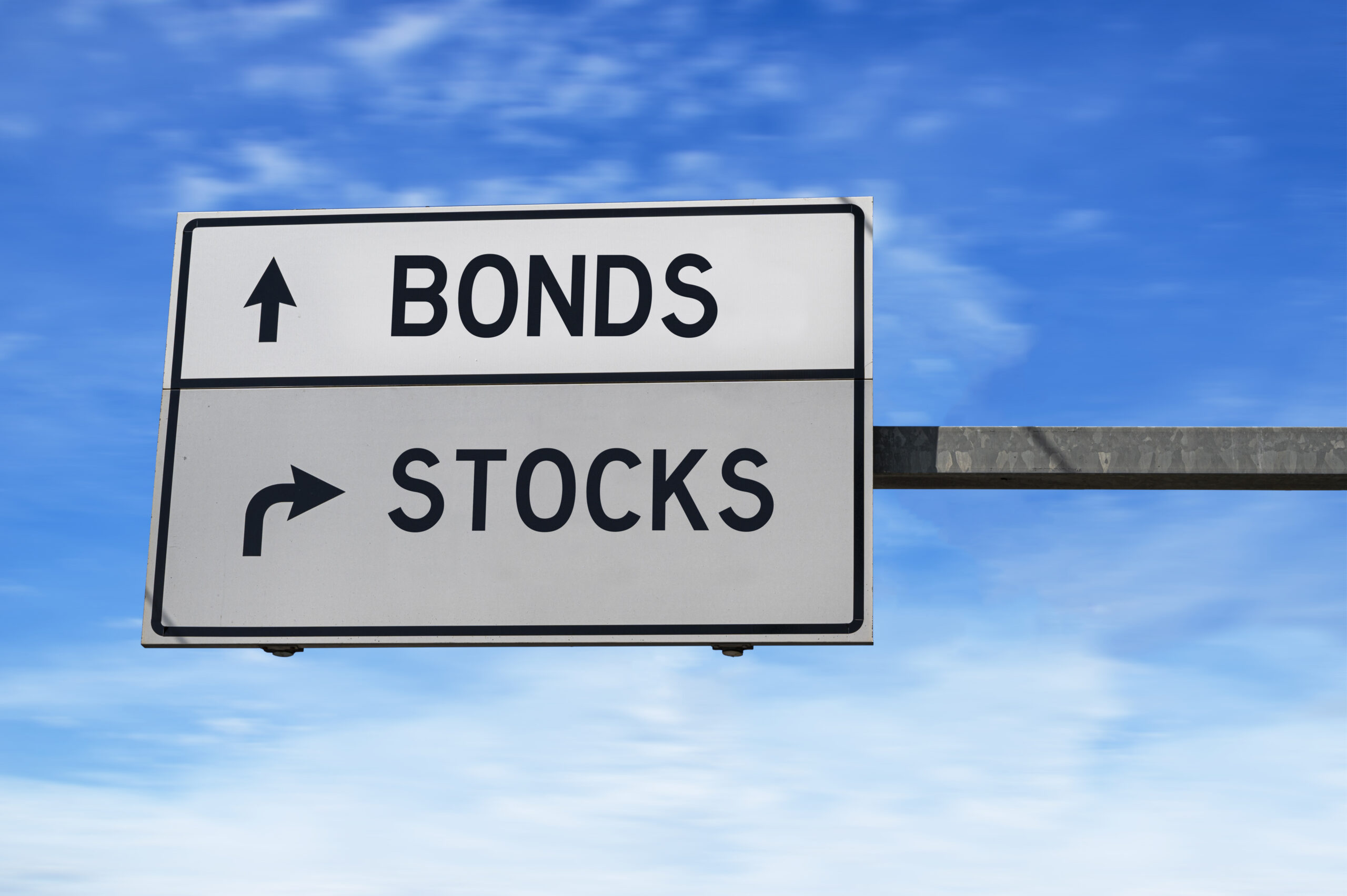 Road sign with words bonds and stocks. White two street signs with arrow on metal pole on blue sky background.