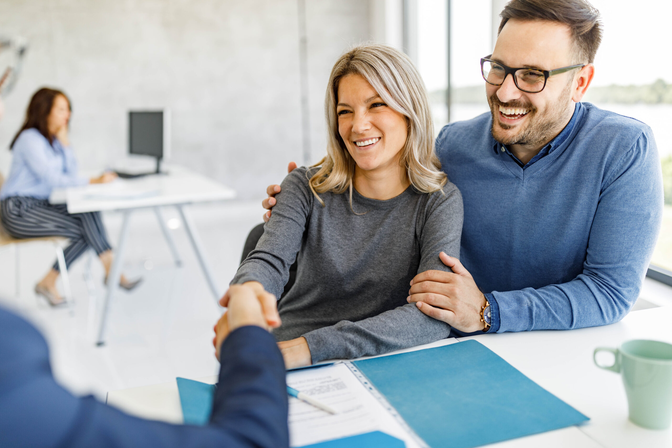 Happy couple came to an agreement with their financial advisor in the office.