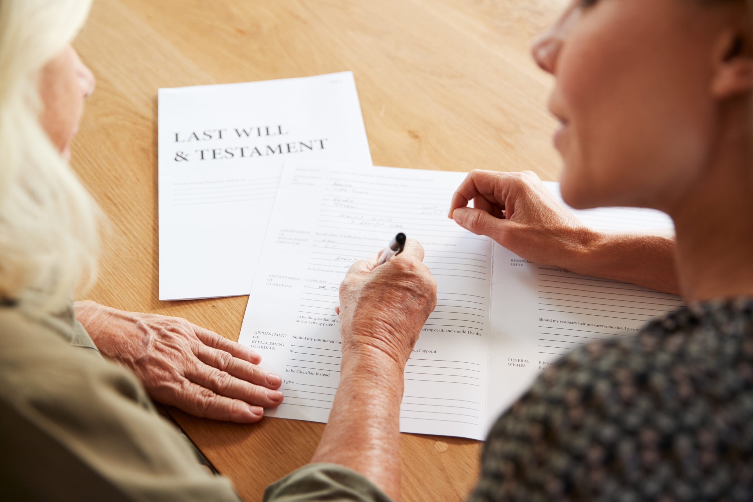 Two women preparing and signing a last will and testament