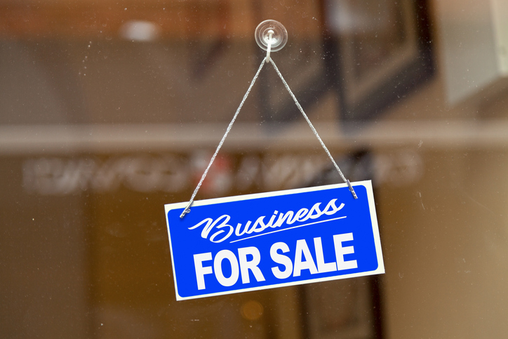 Sign stating “business for sale” hanging on a door.