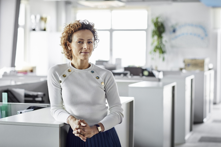 Woman business owner stands in an office smiling