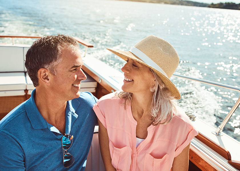 An older couple on a boat on a lake, enjoying their time in the sunshine. Living their financial happily ever after.