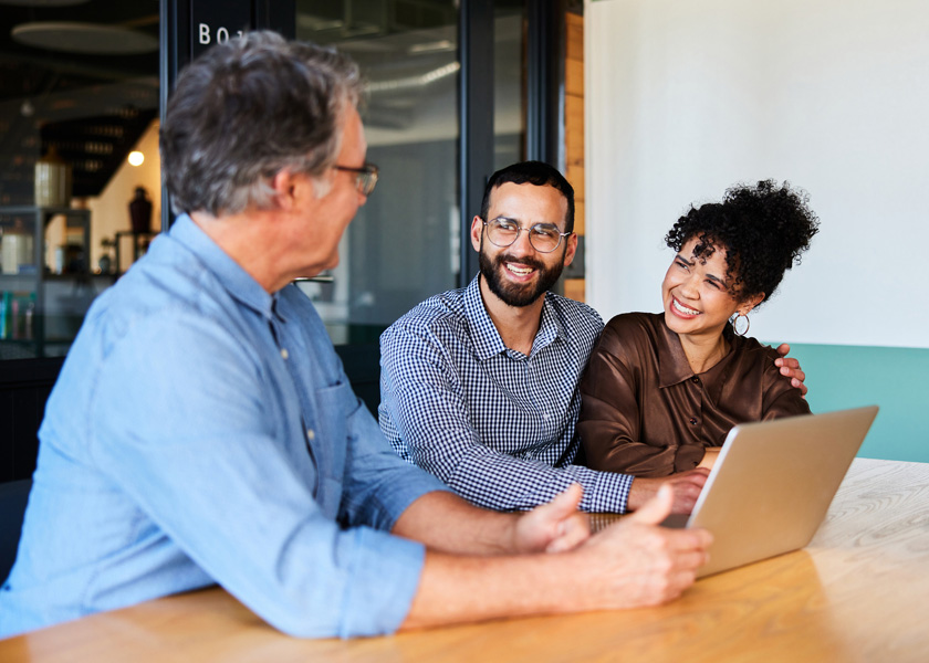 Couple sitting at table and speaking with financial advisor.