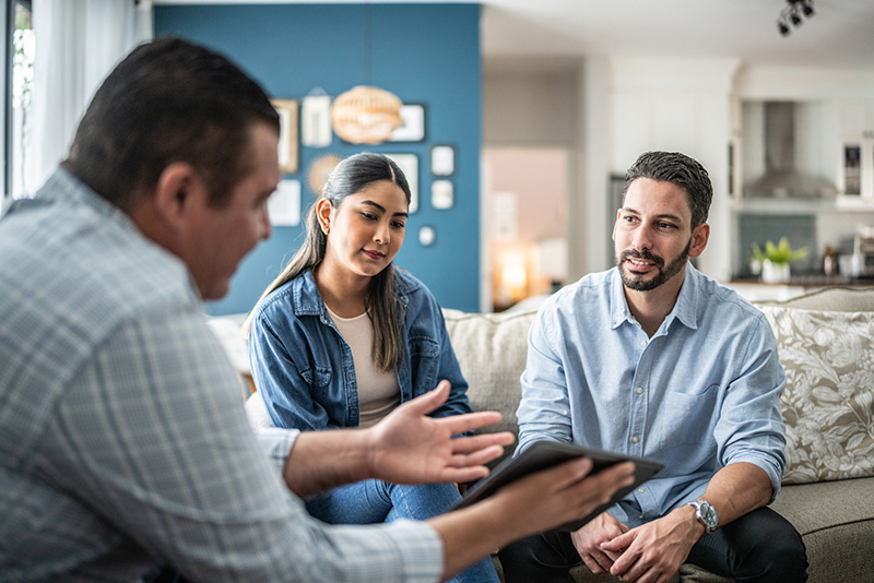 Mid-aged couple seated at a table reviewing financial documents together, representing clients consulting with a wealth advisor.