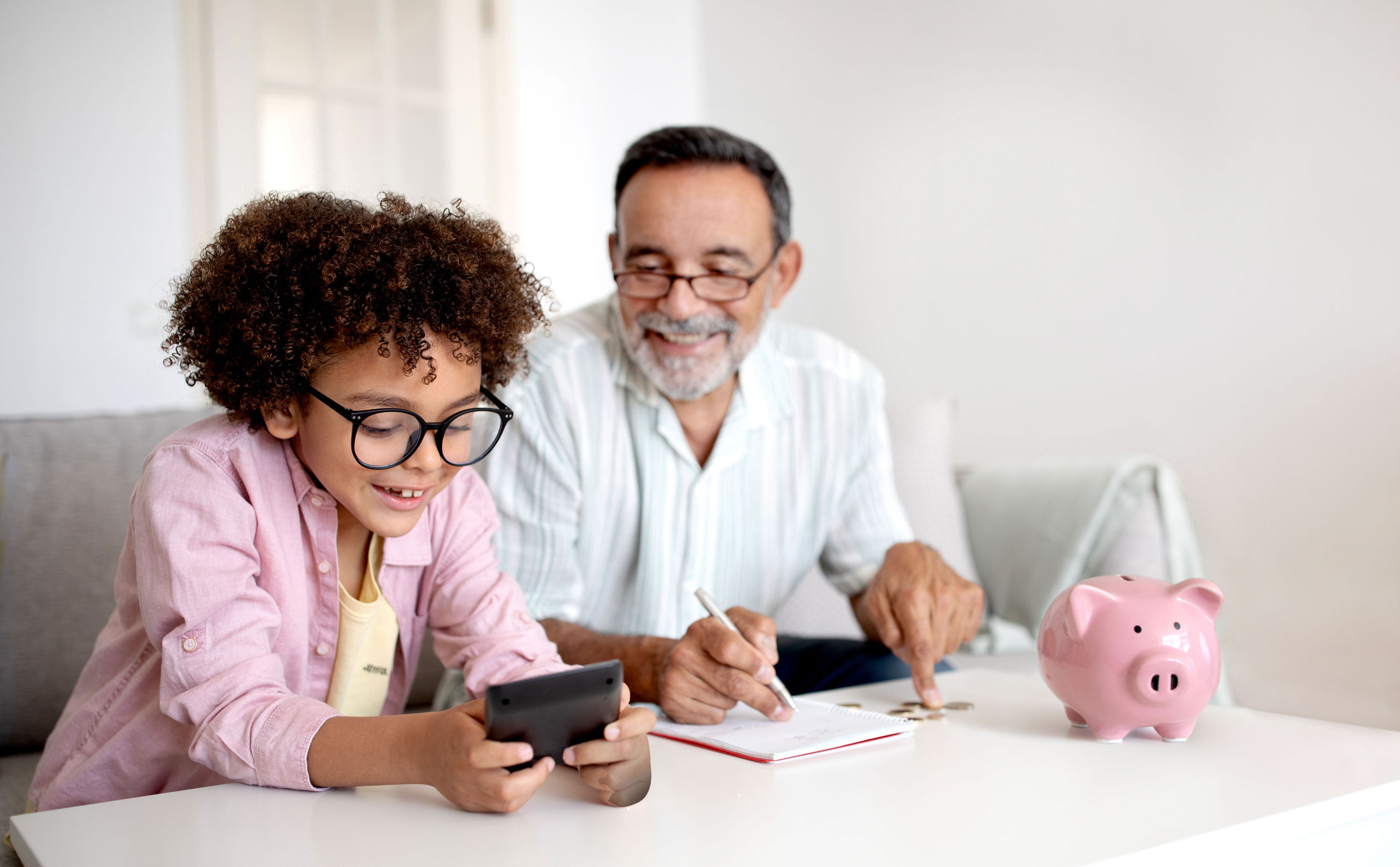 Grandpa and Grandson Engaging in Finance Education Calculating Savings Indoor