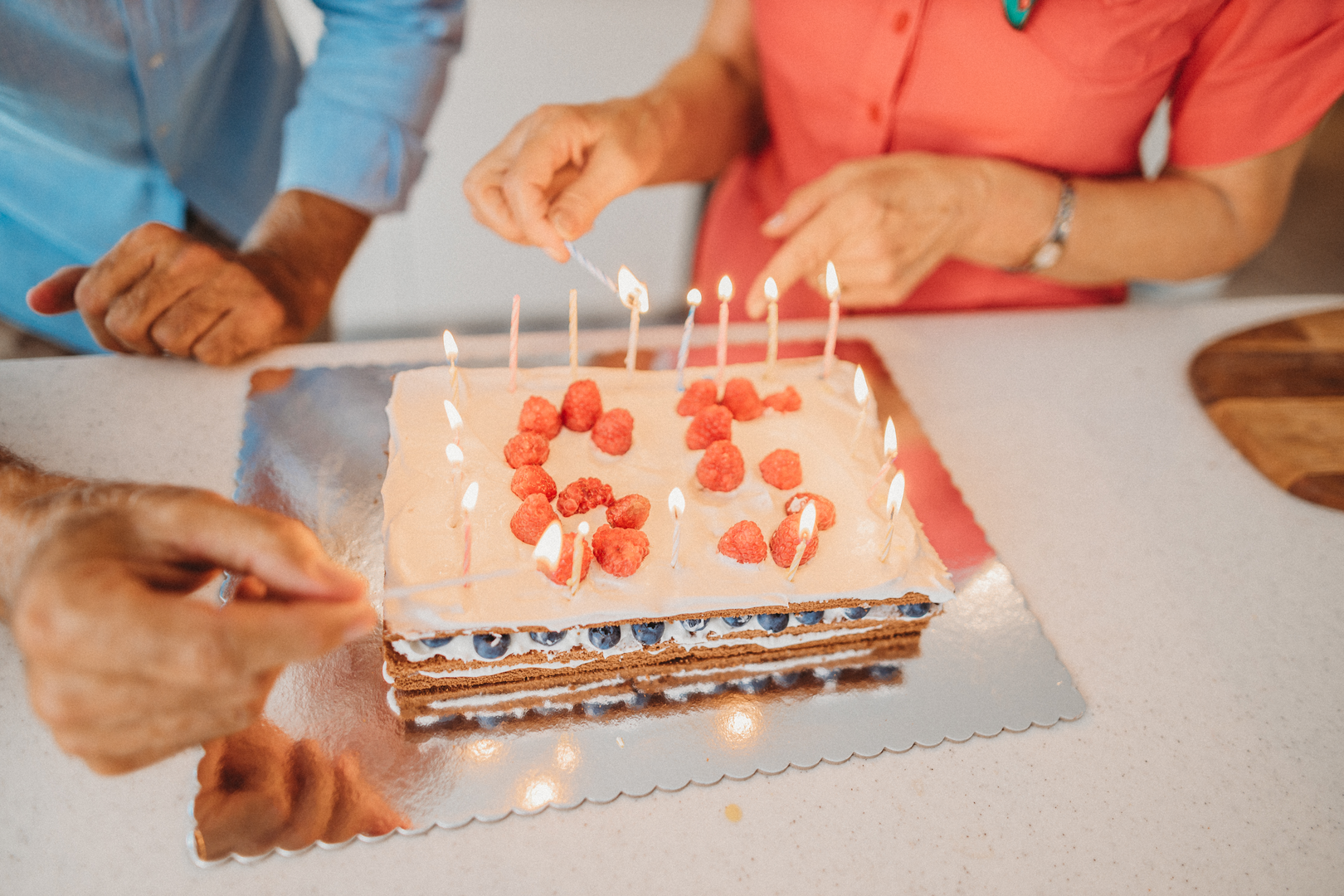 A couple lights candles on a dessert decorated to celebrate a 65th birthday.